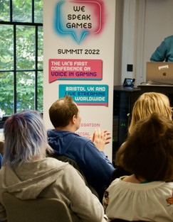 Audience clapping with We Speak Games banner in the background