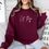 Thumbnail: Maroon sweatshirt with the words Let Them