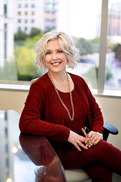 a woman sitting at a desk with glasses in her hand