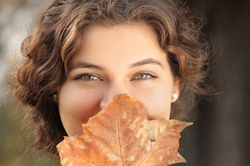 portrait of a close up of a woman covering her face with a leaf