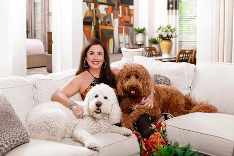 portrait of a woman sits on a couch with two dogs