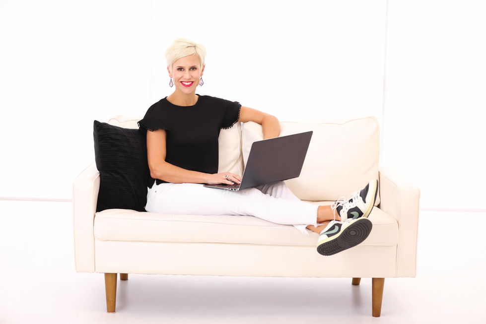 Portrait of a woman sits on a couch using a laptop