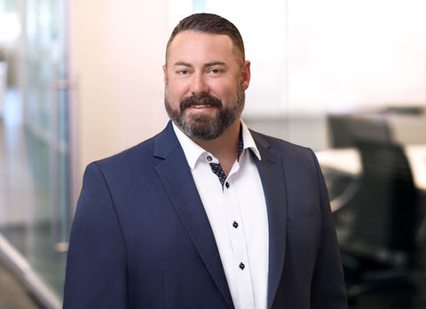 Headshot of a man with a beard is wearing a blue suit and white shirt