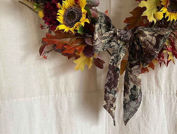 detail of a an autumnal wreath with sunflowers and a bow
