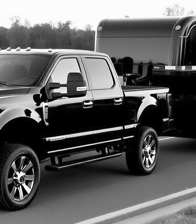 Black Ford F350 dually truck towing a three-car wedge trailer..jpg