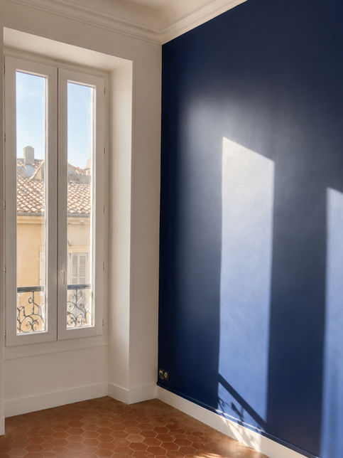 Mur bleu marine et parquet dans une pièce lumineuse.