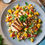 Thumbnail: A mouthwatering dish from Passion Infused Eatery featuring Peachy Salsa Chicken Tenders served on a bed of colorful corn salad on a grey plate. The chicken tenders are generously topped with a vibrant peach salsa, containing white and yellow corn, cilantro, onion, bell peppers, and more. Each tender is tender and juicy, promising a burst of flavor with every bite. 