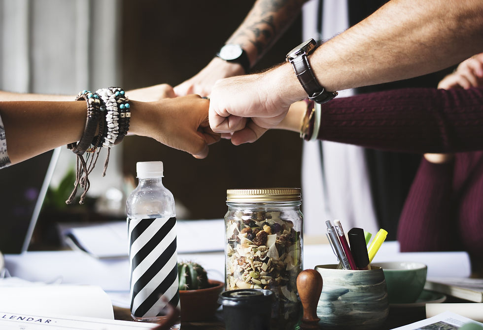 Five colleagues putting their fists together to get work done