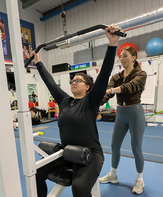 PT adjusting client's posture on the lat pull down