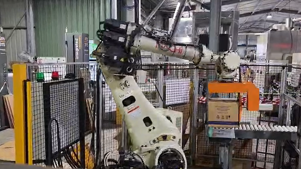 Close-up view of NACHI robot gripper holding 5 cartons