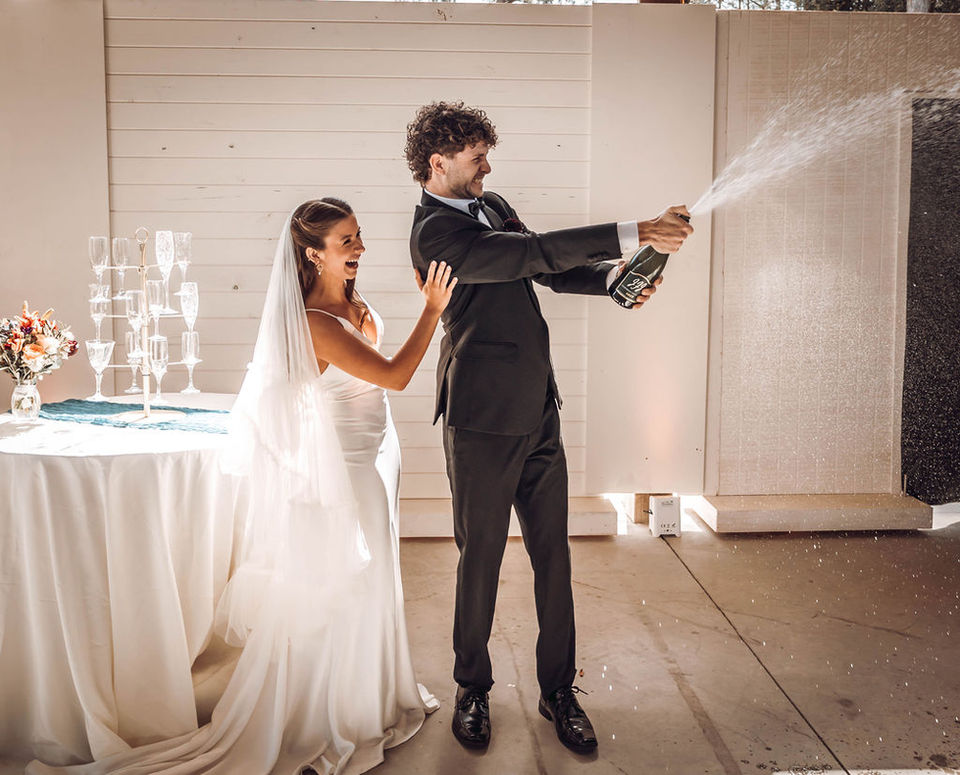 Bride and groom laughing and popping champagne