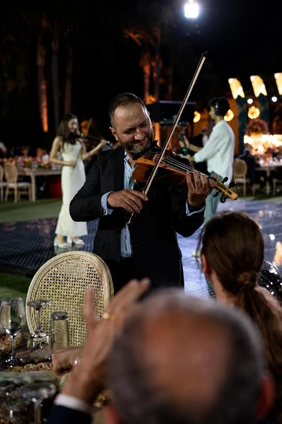 Fahed Hawa performs violin at an outdoor reception as guests watch