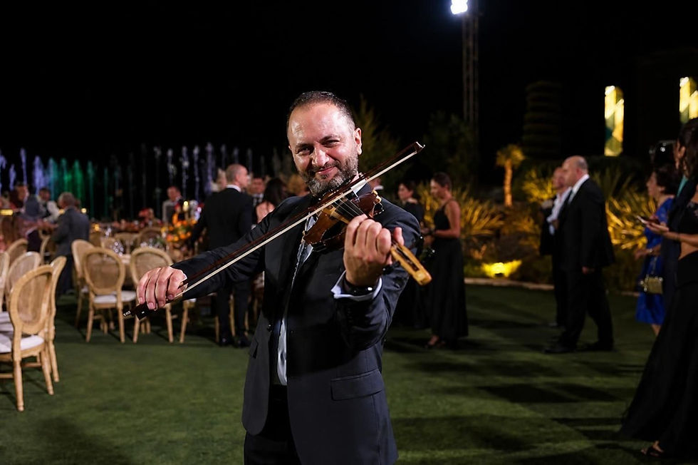 Fahed Hawa seated and playing violin in a light blue shirt