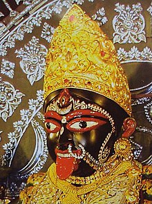 Close-up of a decorated Kali idol, with traditional ornaments and expressive eyes.