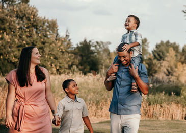A dad gives his sun a piggy back during a family walk outside.
