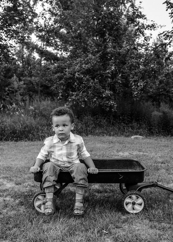 A little boy sits contently in his favourite red wagon.