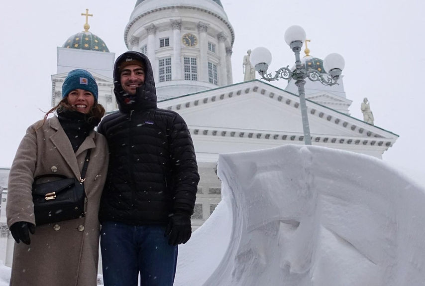 A couple posing in front of the Helsinki Cathedral, on the side of massive amount of snow.