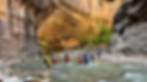 High school students on an outdoor adventure walking through water and high rock cliffs