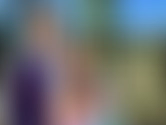 Family standing outdoors with two children, smiling in front of a fence and mountain landscape