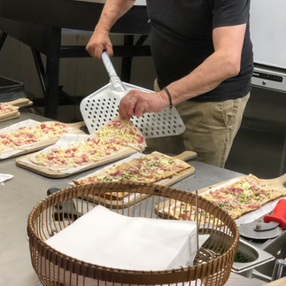 chef getting the flammekueche flatbread ready to bake in the oven