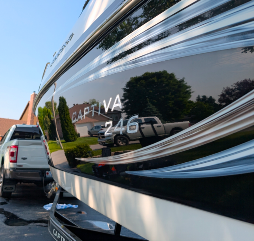 Close-up of a glossy black and white Rinker Captiva 246 motorboat on a trailer, reflecting