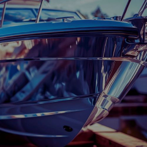 Close-up of a boat’s bow with a glossy, freshly restored gelcoat finish, reflecting its su