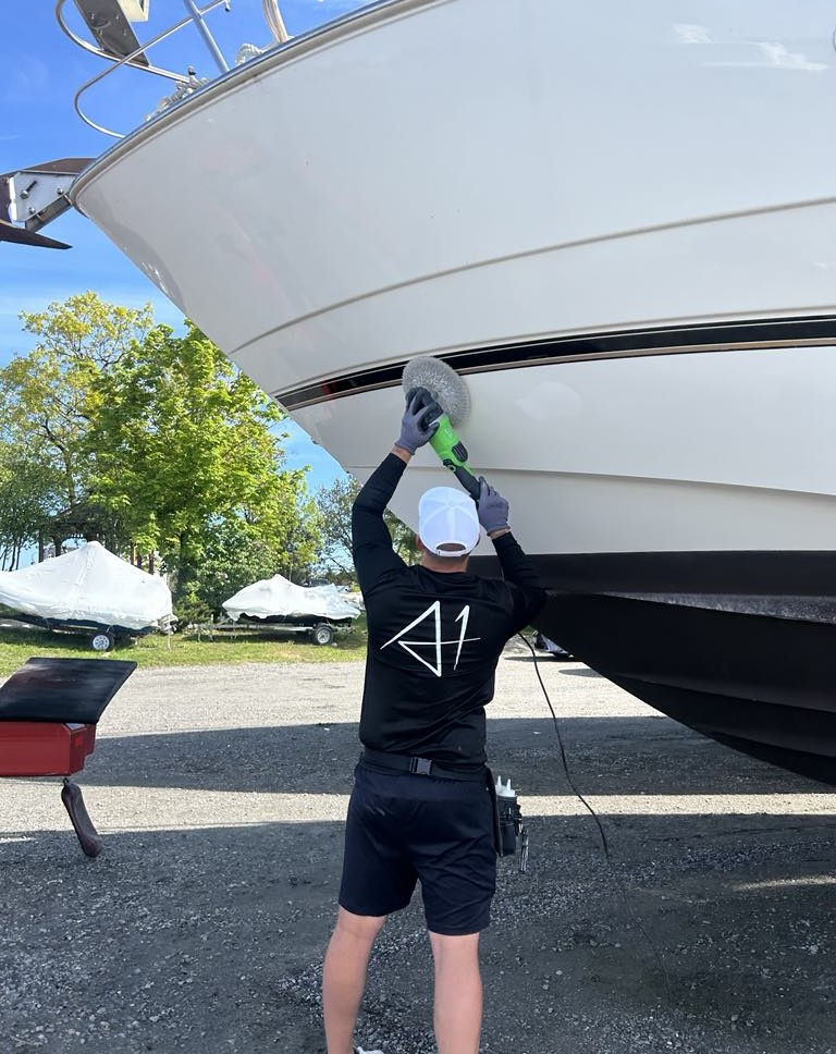An A1 Marine Care technician polishing the port side of a hall at a marina in Georgian Bay