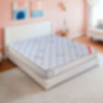 White bed with a mattress and comforter in a bedroom setting.