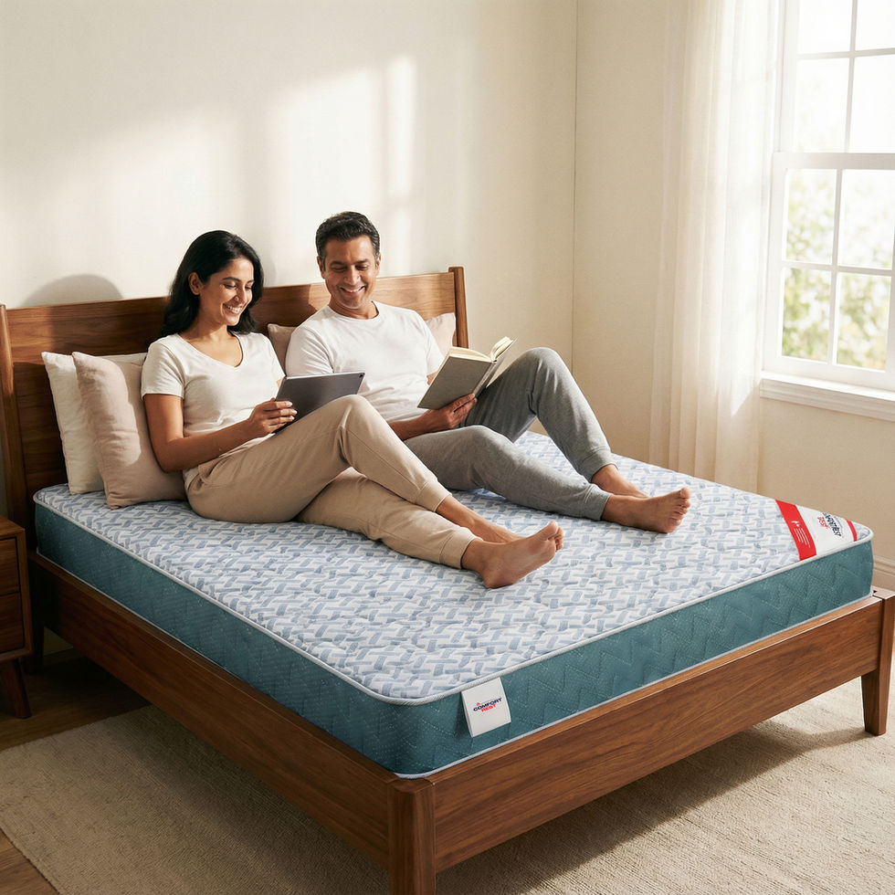 Couple relaxing on a bed with a tablet and book near a window.