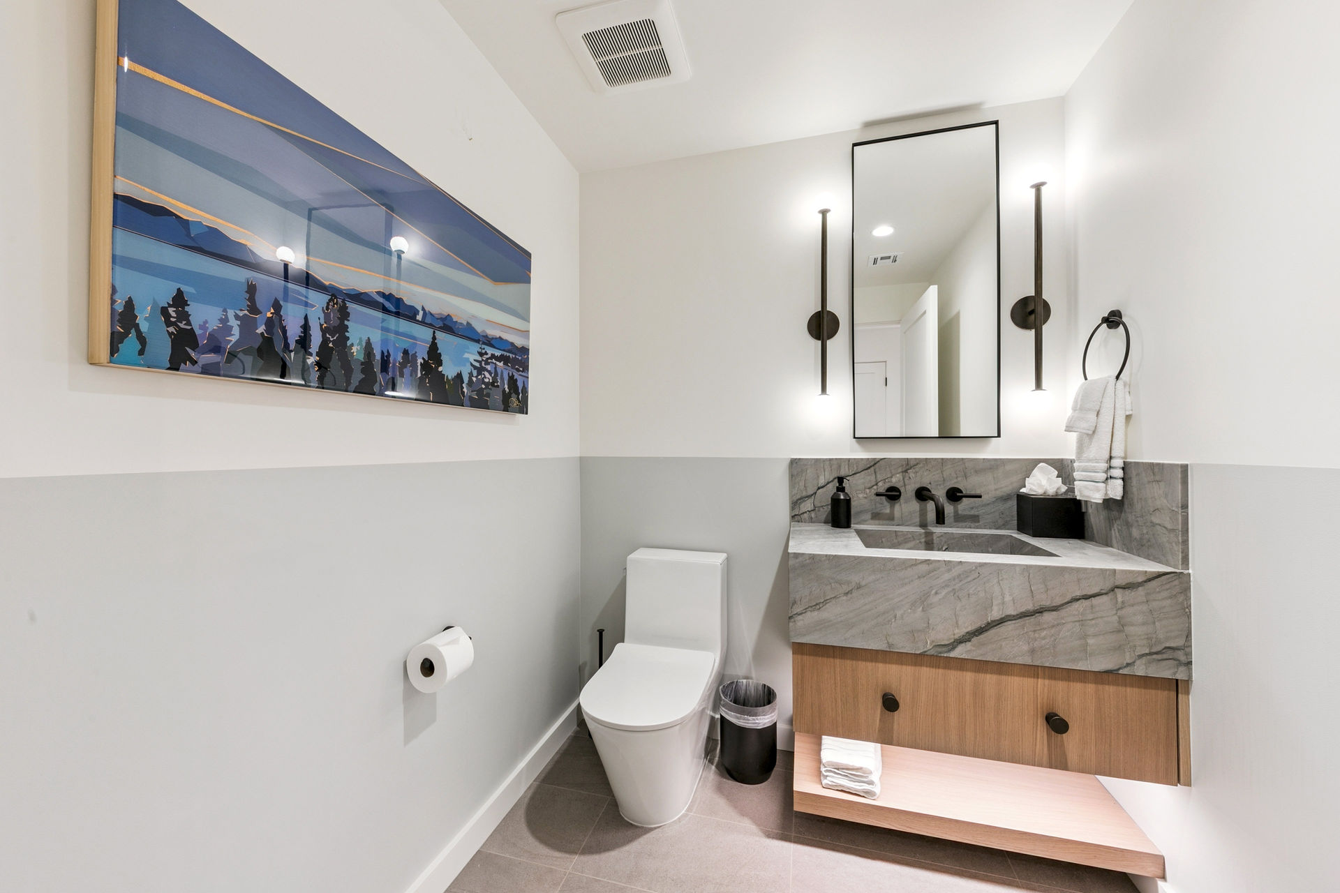 This powder room makes a powerful statement with a floating vanity and a dramatic integrated sink carved from a single piece of heavily-veined stone, creating a piece of functional art.