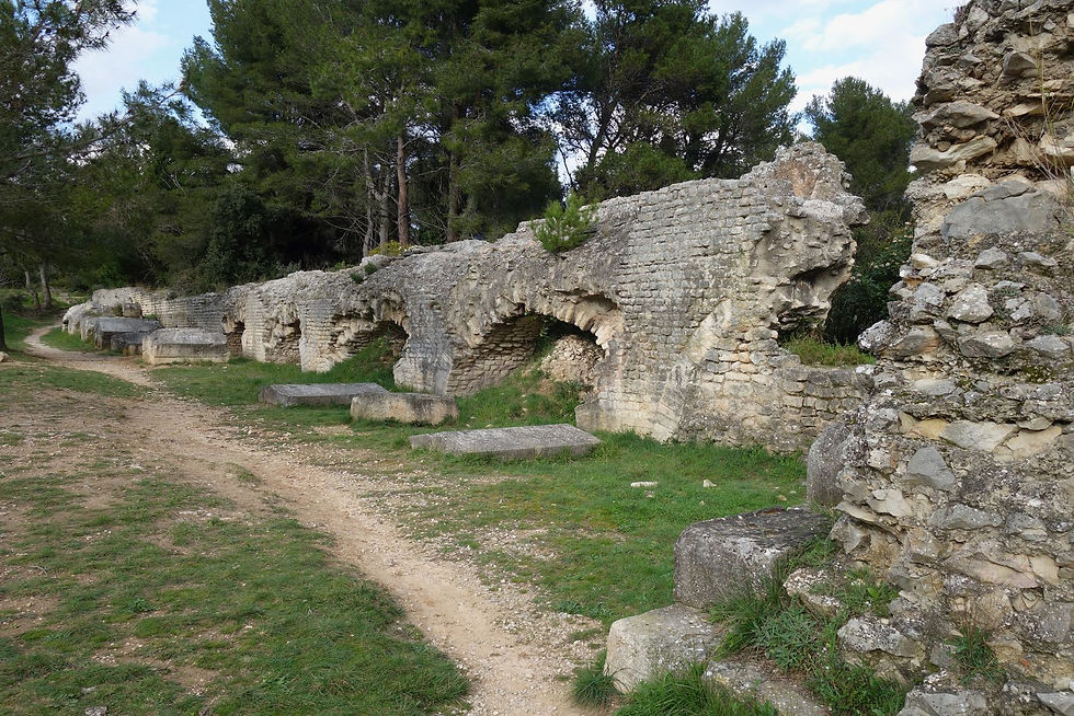 A stone arched aqueduct with a dirt path running along side.
