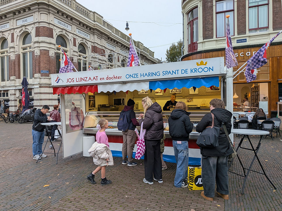 A fish vendor stand in a pedestrian plaza. Many people standing at the stall, ordering and eating.