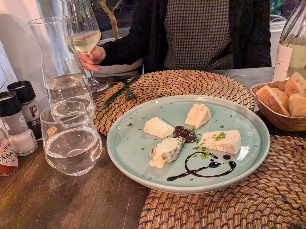 A cheese plate with four cheeses and a marmalade in the center.