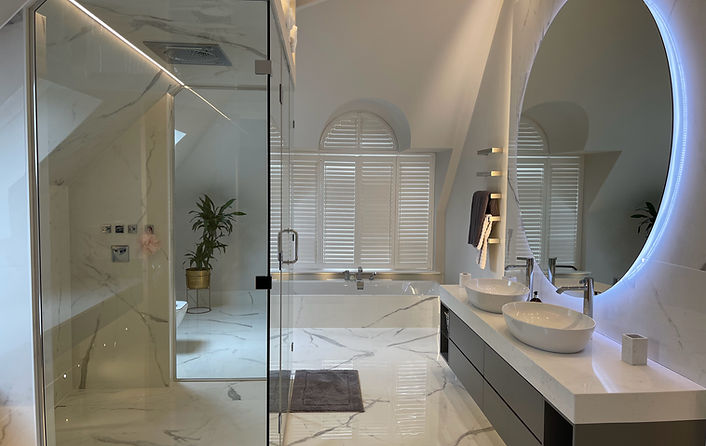luxury bathroom with marble floors and lip up round mirror with lutron lighting