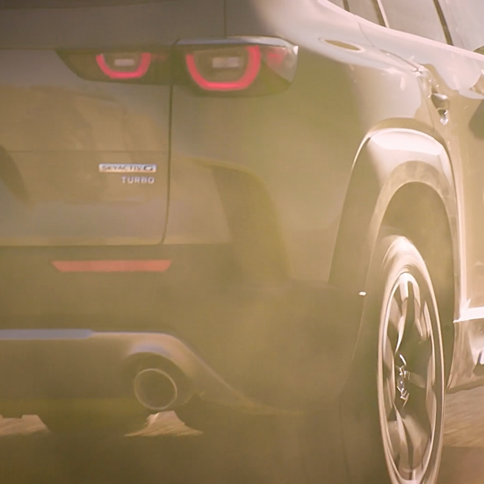 Close-up of a Mazda steering wheel with hands gripping it, highlighting the car's premium interior and driver-focused design.