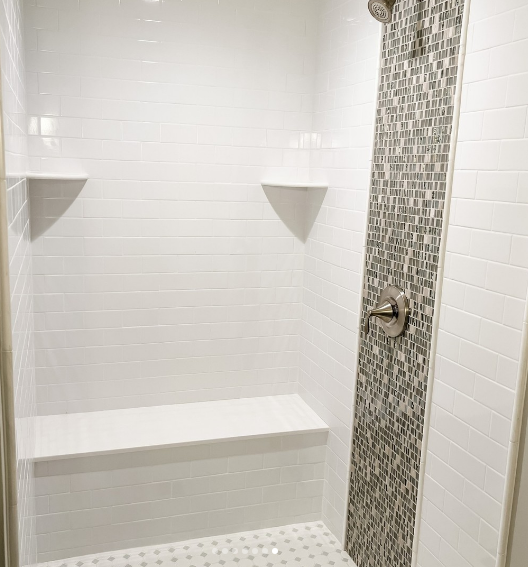 White tiled shower with built-in bench and mosaic accent wall. Modern Bathroom Designs.