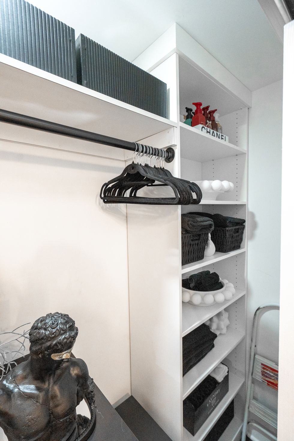 Custom white closet with shelves and clothes with boxes and stylish accessories.