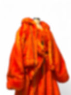 Orange faux fur couture bomber jacket with oversized sleeves displayed on mannequin in studio.
