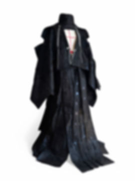 Black avant-garde couture kimono with layered panels and chain detailing displayed in studio.