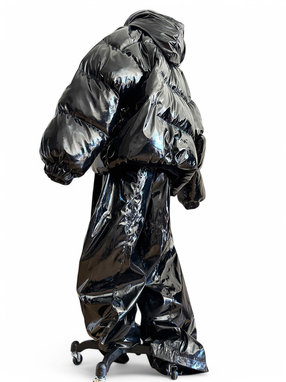 Black glossy PVC wide-leg couture trousers displayed on mannequin in studio.