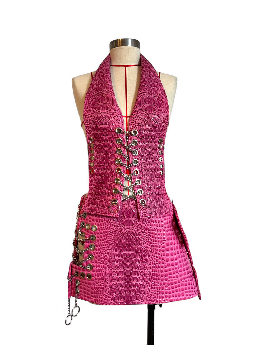 Pink textured couture mini skirt with silver eyelets and chain lacing displayed in studio.