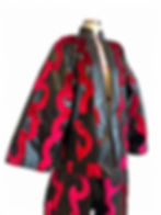 Black leather couture jacket with red flame appliqué panels displayed on mannequin in studio.