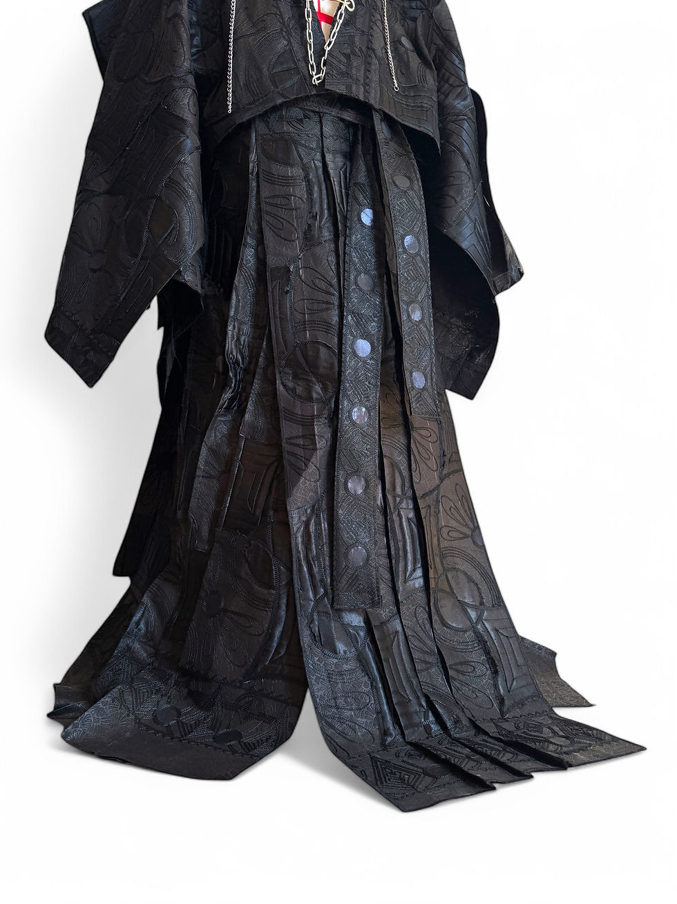 Black avant-garde couture trouser with skirt with layered panels and chain detailing displayed in studio.