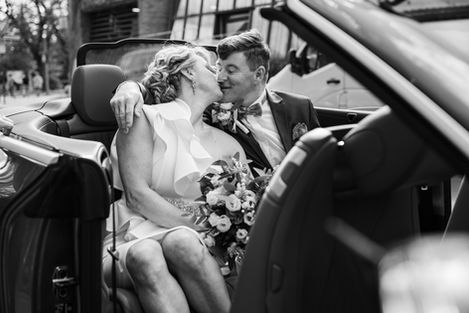 Brautpaar küsst sich im Cabrio mit Brautstrauss – Hochzeitsreportage Berlin