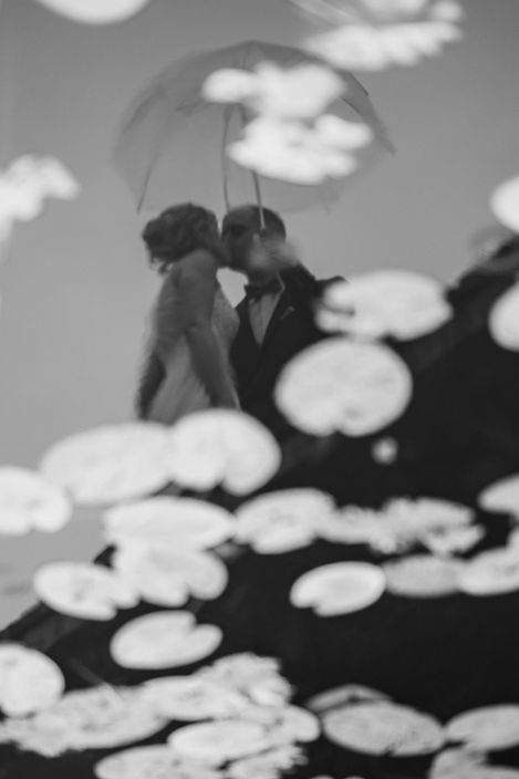 Brautpaar mit Regenschirm gespiegelt im Seerosenteich – kreative Hochzeitsfotografie Berlin