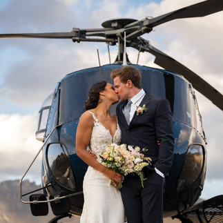 Banff helicopter elopement couple kissing in front of helicopter on a mountain summit