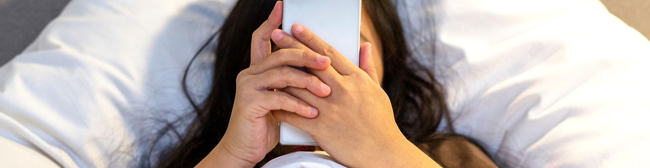 Woman laying in bed looking at cellphone
