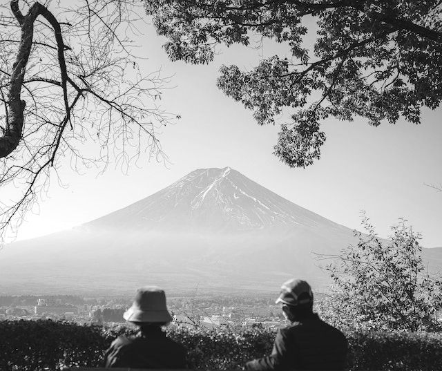 Elderly couple sitting on a bench together in front of a mountain