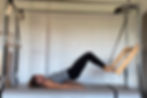 Woman on the Pilates Cadillac doing shoulder roll down