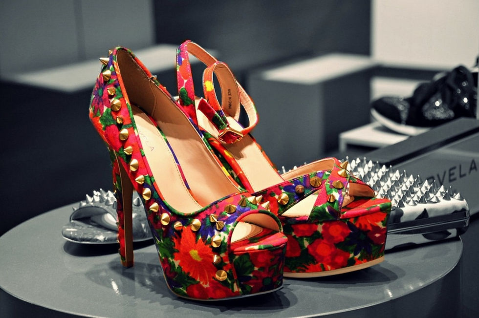Bold floral platform stiletto heels with gold studs displayed in a luxury boutique setting, representing expressive identity, statement leadership style, and high-end women-centric branding aesthetics.